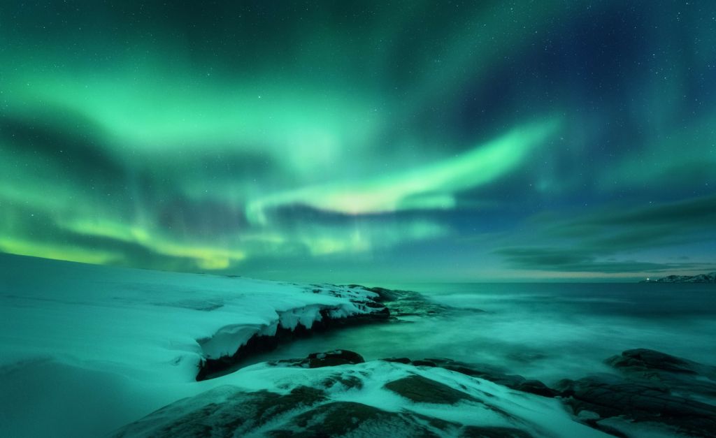 Des aurores boréales vertes au-dessus des rochers enneigés