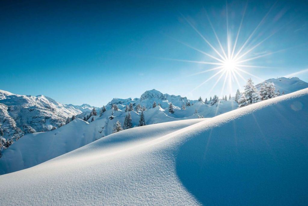 Lumière du soleil sur des collines enneigées scintillantes.