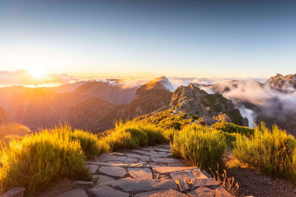 Lever de soleil au-dessus d'un sentier de montagne et des nuages.