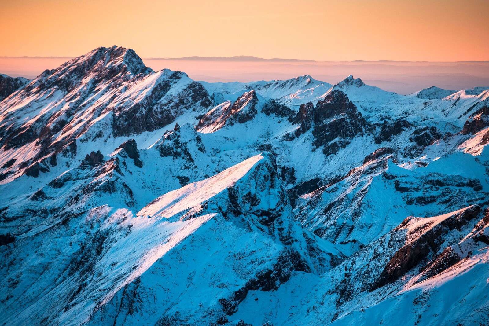 Lever du soleil sur un massif montagneux enneigé.