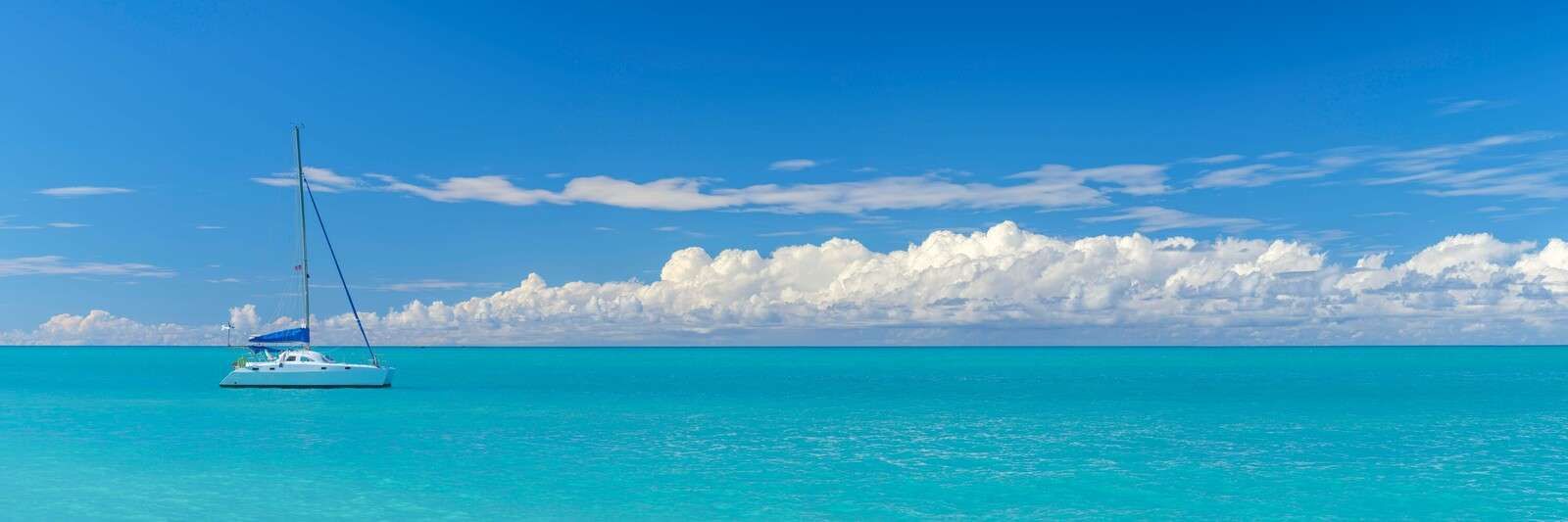 Vue panoramique d'un paysage marin bleu avec voilier et ciel nuageux